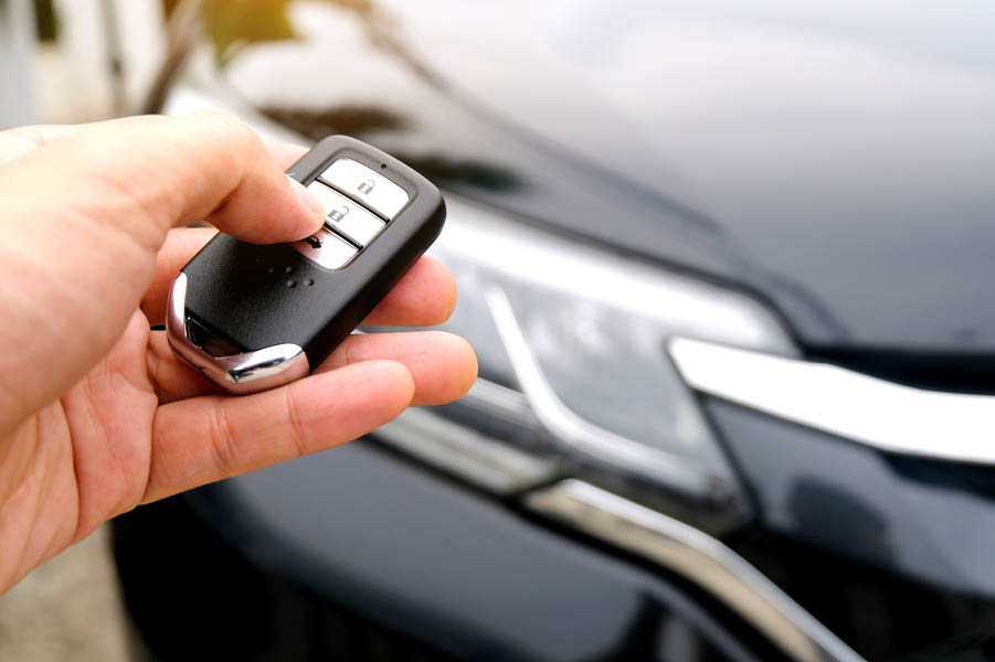 Ready to Beat the Weather? The Comfort of a Remote Car Starter Explained; Man hand holding the car remote, he push the remote control to open the car door