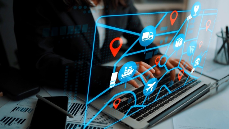 Hands typing on laptop with supply chain logistics icons