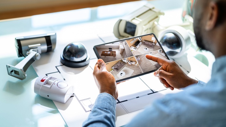 Man viewing home security camera feeds on tablet device