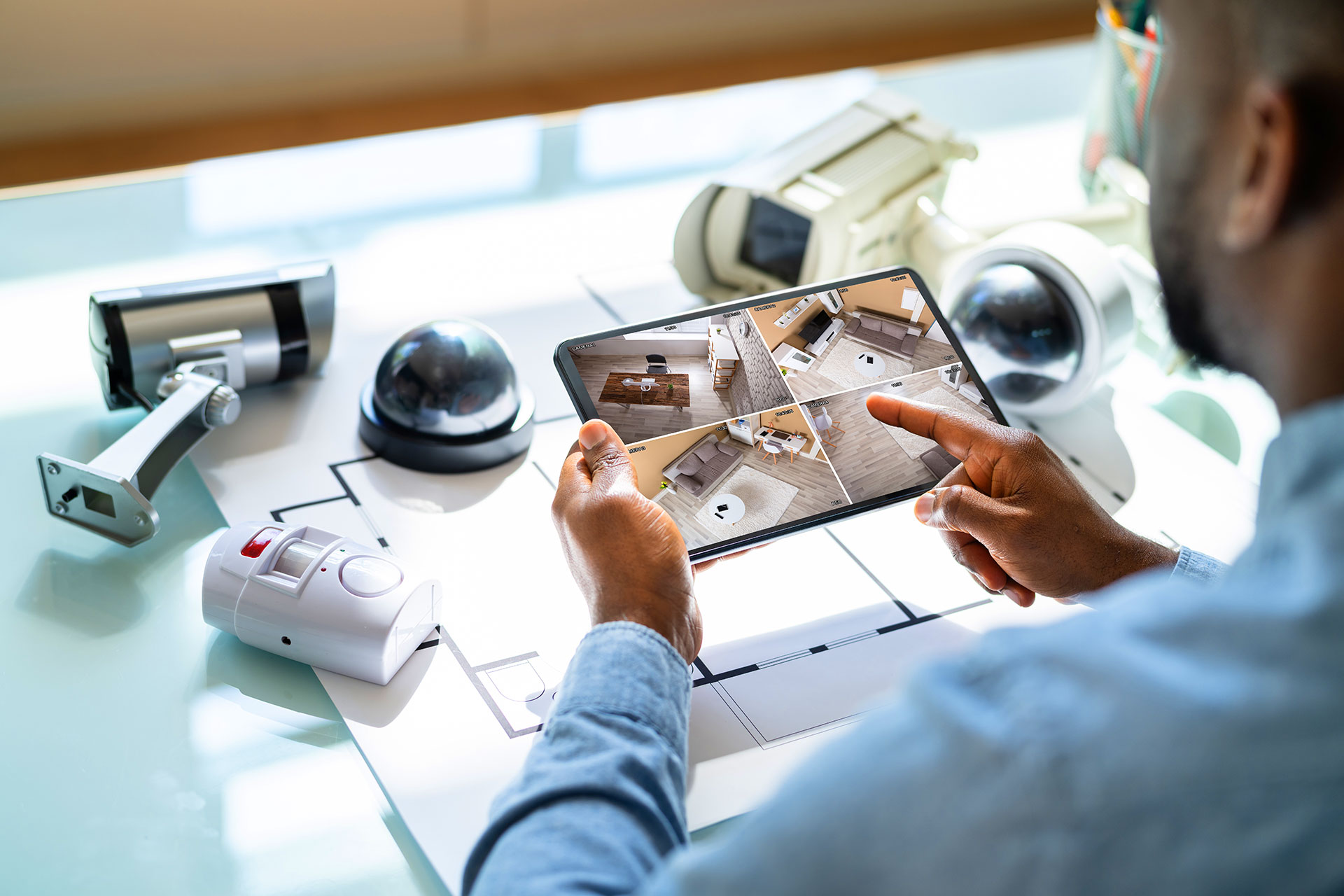 Man viewing home security camera feeds on tablet device